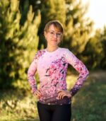 Damski longsleeve sportowy Sakura LOCO na modelce z rękami na biodrach, widoczny różowy przód z kwiatami wiśni i ciemniejszym dołem.