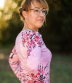 Damski longsleeve Sakura LOCO na modelce z boku, widoczny długi rękaw, linia ramienia i kwiatowy wzór na różowym tle.