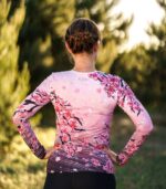 Longsleeve sportowy damski Sakura LOCO na modelce z tyłu, widoczne kwiaty wiśni na plecach, długie rękawy i ciemniejszy dół koszulki.