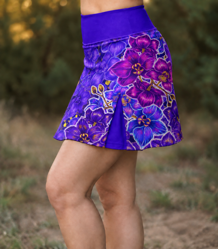 Boczny widok spódniczki Nocna Orchidea LOCO na modelce, z wysokim fioletowym pasem, nadrukiem orchidei i fioletową wstawką.