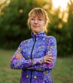 Modelka w bluzie damskiej Nocna Orchidea LOCO ze skrzyżowanymi rękami, widoczny kwiatowy wzór na przodzie i rękawach.