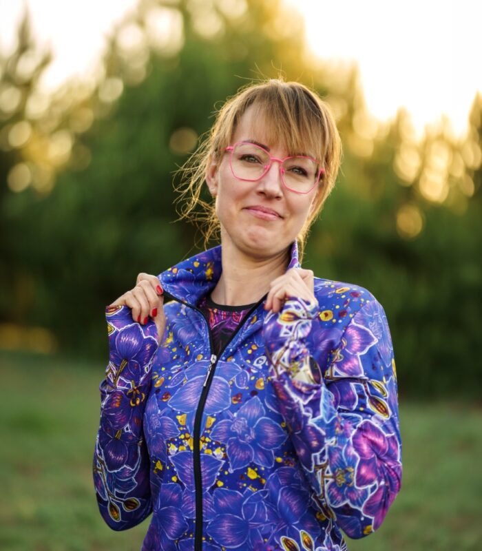 Bluza Nocna Orchidea LOCO na modelce z częściowo rozpiętym zamkiem, widoczna stójka i fioletowe kwiaty.