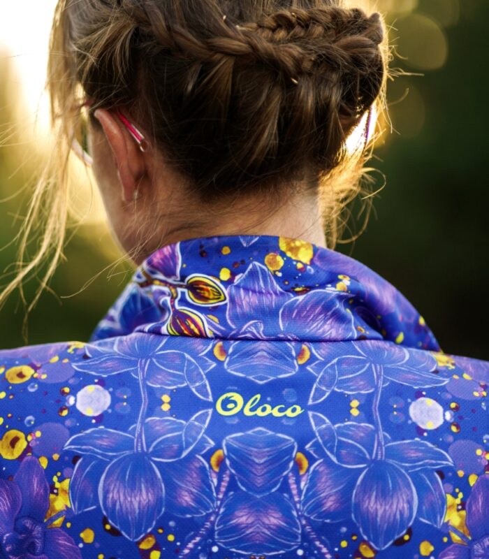 Zbliżenie stójki i górnej części pleców bluzy Nocna Orchidea LOCO, widoczne żółte logo oraz kwiatowy wzór.