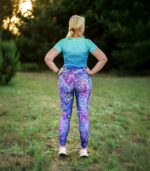 Długie legginsy sportowe Nocna Orchidea LOCO na modelce z tyłu, widoczny pas i wzór kwiatów na całych nogawkach.