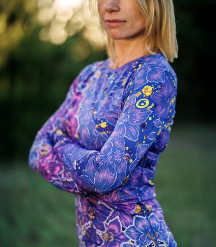Zbliżenie rękawa longsleeve’u damskiego Nocna Orchidea LOCO, widoczne żółte logo na ramieniu i kwiatowy wzór.