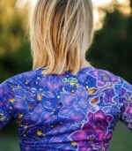 Zbliżenie górnej części pleców longsleeve’u Nocna Orchidea LOCO, widoczne żółte logo pod dekoltem i fioletowo-niebieskie orchidee.