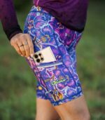 Krótkie legginsy damskie Nocna Orchidea LOCO, zbliżenie bocznej kieszeni z telefonem, żółtego logo i fioletowych orchidei.