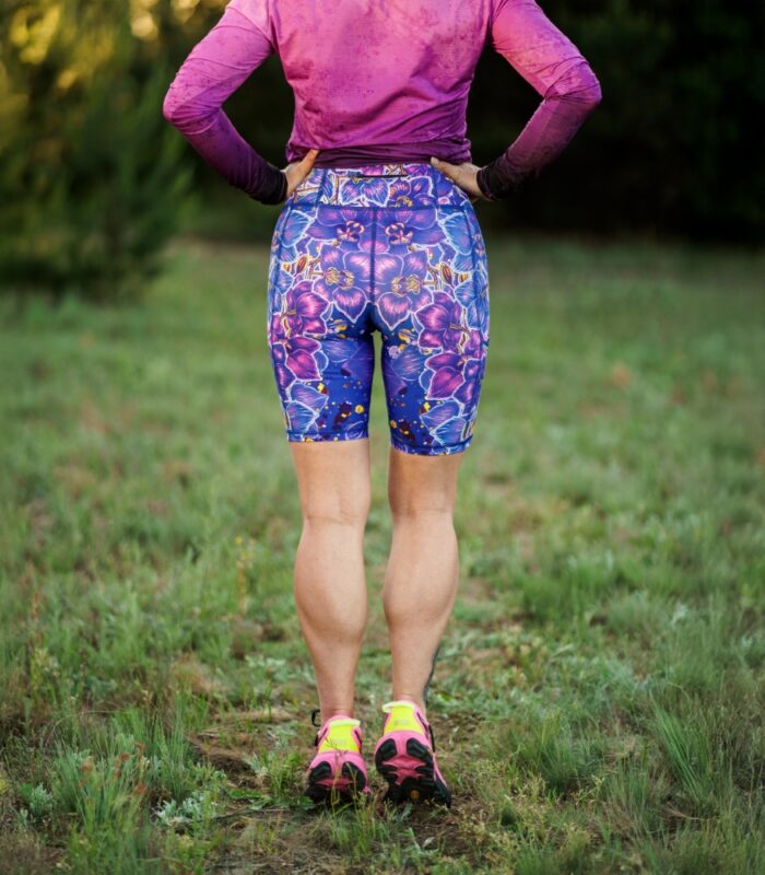 Krótkie legginsy sportowe Nocna Orchidea LOCO na modelce z tyłu, widoczny pas, długość nogawek i kwiatowy wzór.